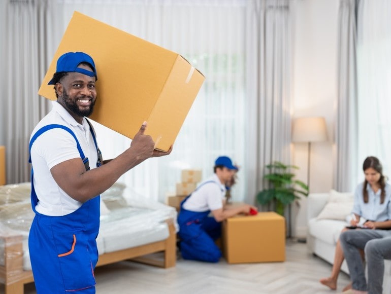 Delivery team unloading boxes of furniture in a customer’s living room