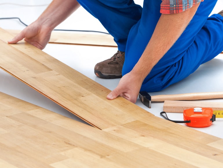 Flooring technician locking laminate floor planks during installation